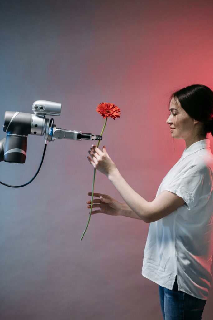 pexels photo 8438979 8438979 A woman interacts with a robotic arm holding a flower, symbolizing human-technology harmony.